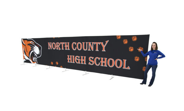 photo of woman standing next to thirty foot long renovate partition with snarling tiger head graphic and north county high school