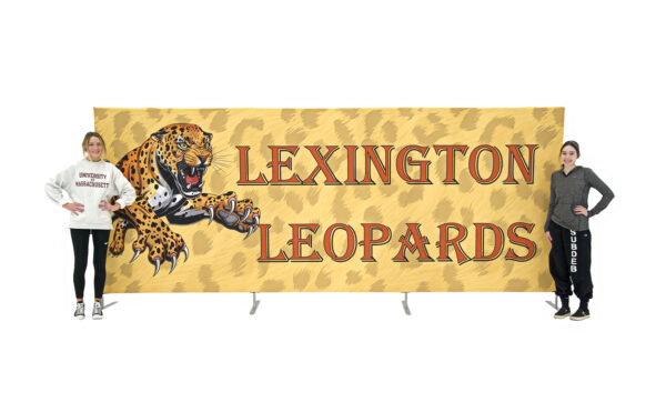 photo of two women standing next to fifteen foot long renovate partition with snarling leopard pouncing graphic and lexington leopards